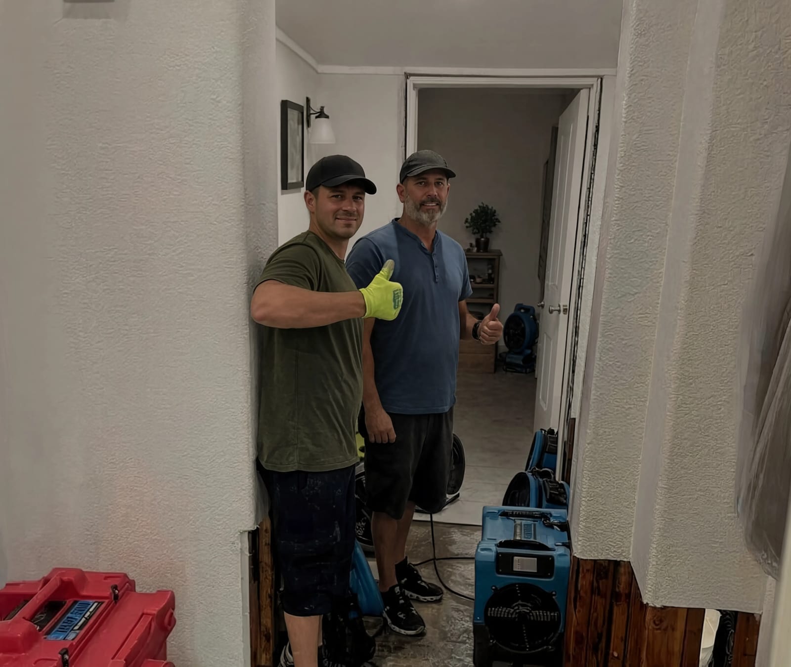 Two technicians with air movers running in a hallway