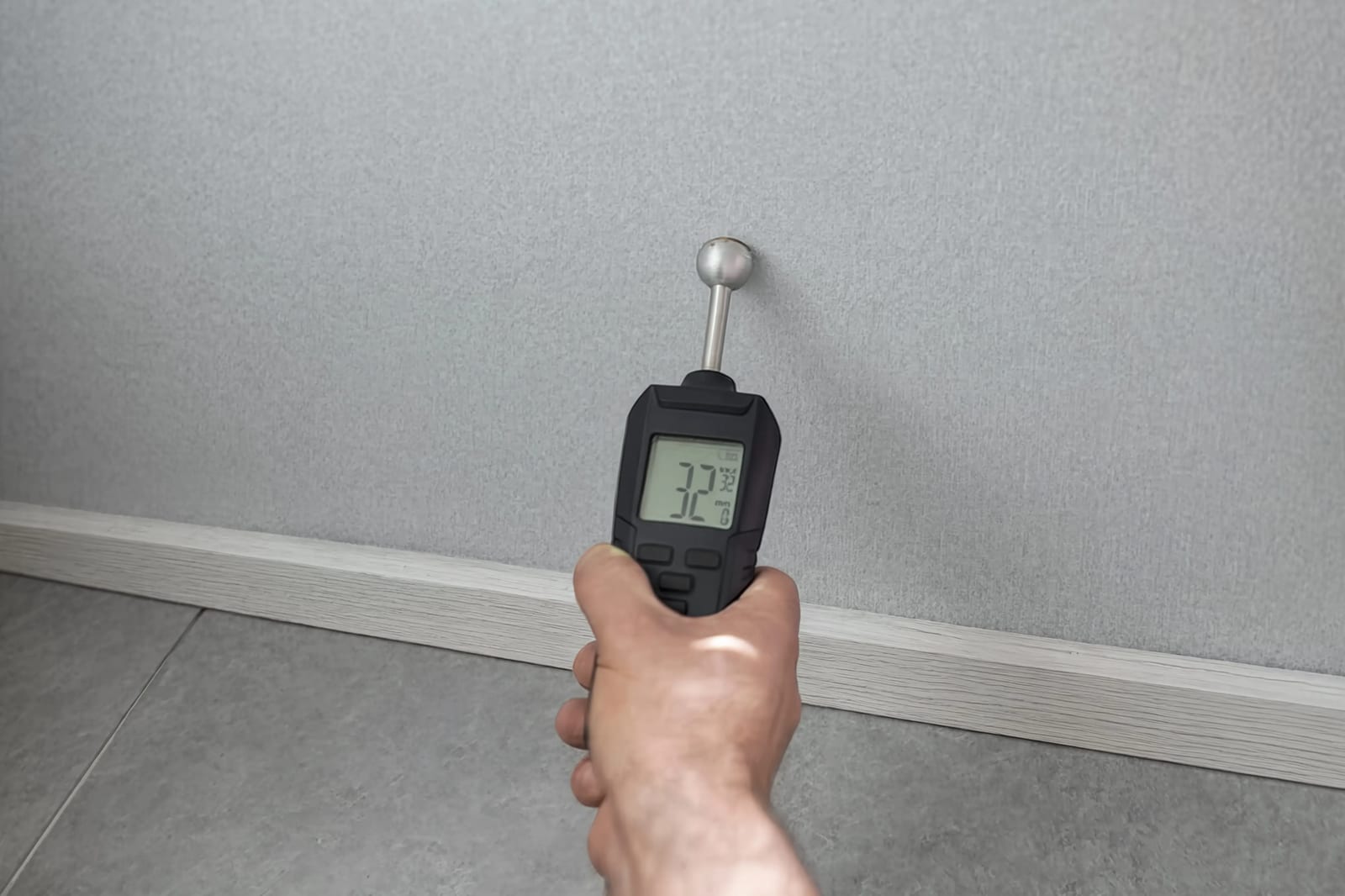 A moisture meter held against a wall