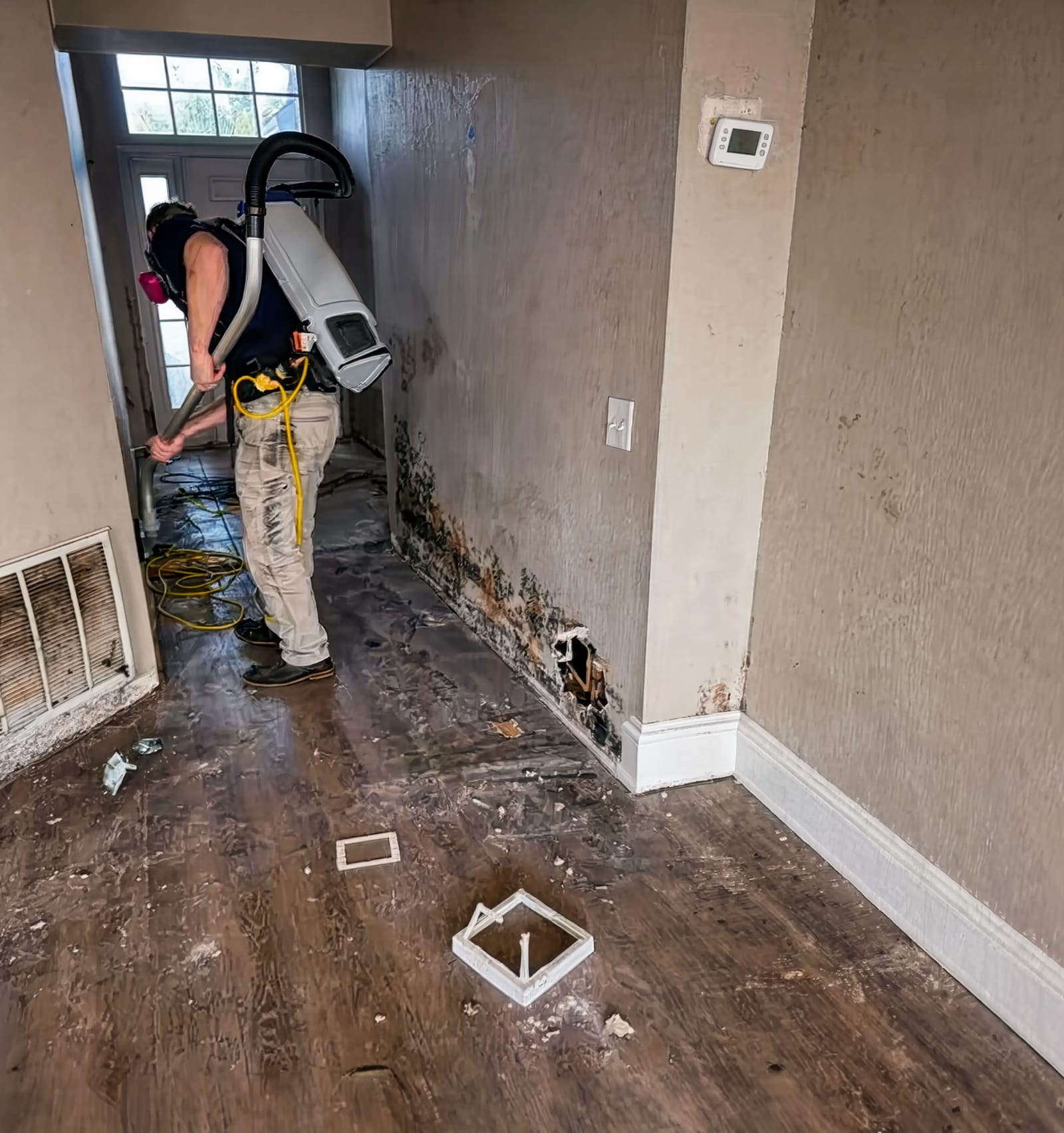 A technician running a HEPA vacuum along a wall
